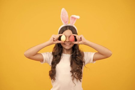 Photo for Happy teen girl in bunny ears hold eggs on yellow background, easter. - Royalty Free Image