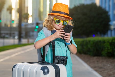 Téléchargez les photos : Portrait d'enfant voyageur heureux avec des bagages. Petit touriste positif avec valise prête à voyager. Happy kid touriste avec des bagages va voyager en vacances - en image libre de droit