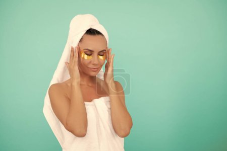 young woman in shower towel with golden patch. copy space.