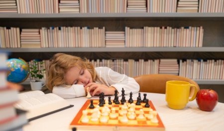 Photo for Tired child sleeping near chess in classroom. Chess school and education concept - Royalty Free Image