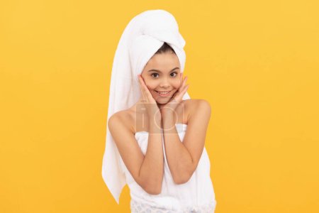 Foto de Cheerful teen child in shower towel with cream on face. - Imagen libre de derechos
