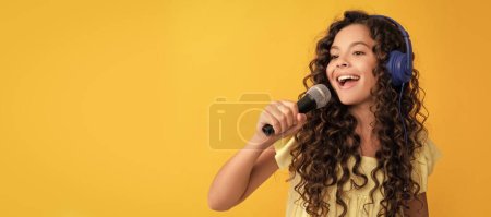 cheerful teen girl listen music in headphones and singing in microphone, vocal school. Child portrait with headphones, horizontal poster. Girl listening to music, banner with copy space