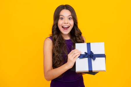 Teenage kid with present box. Teen girl giving birthday gift. Present, greeting and gifting concept. Excited face, cheerful emotions of teenager child girl