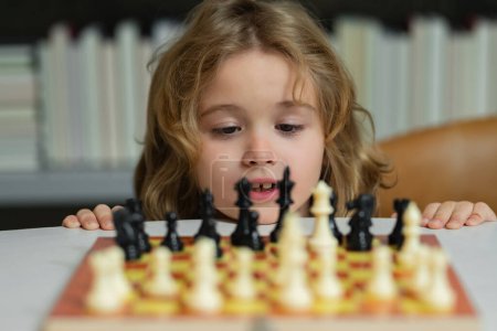 Photo for Little child play chess. Kid playing board game. Thinking child brainstorming and idea in chess game. Kids early development. Boy kid playing chess at home. Portrait close up, funny face - Royalty Free Image
