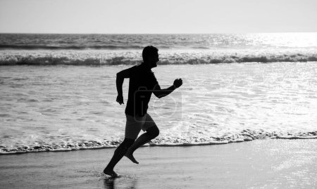 Téléchargez les photos : Silhouette de coureur homme athlétique courant sur la plage d'été, sport. - en image libre de droit