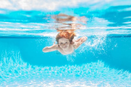 Child underwater swim in the swimming pool. Cute kid boy swimming in pool under water