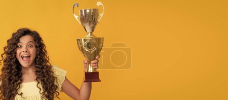 Photo for Amazed kid holding golden champion cup and shampoo bottle, hair care. Horizontal poster of isolated child face, banner header, copy space - Royalty Free Image