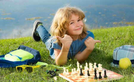 Foto de Inteligente niño concentrado y pensante jugando ajedrez - Imagen libre de derechos