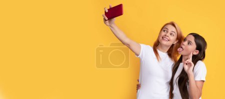 Foto de Mother and daughter kid banner, copy space, isolated background. happy cool mom and kid making selfie on phone, content maker - Imagen libre de derechos