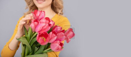beschnittene Frau mit Tulpen. Dame halten Blumen für den Frühlingsurlaub. Mädchen mit Strauß auf grauem Hintergrund. Blumengeschenk zum Frauentag. 8. März und Muttertag. Kopierraum.