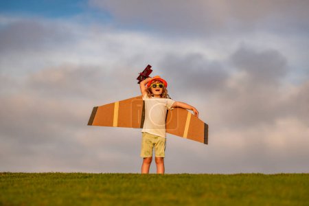 Foto de Niño pequeño está jugando y soñando con volar sobre las nubes. Concepto de infancia. pequeño lindo chico jugando con un juguete avión alas - Imagen libre de derechos