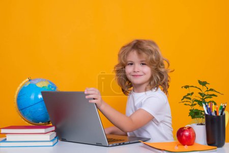 School child portrait isolated on yellow studio background. School child using laptop computer. Clever schoolboy learning. Kids study, knowledge and education Poster 656459106