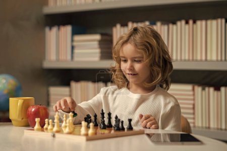 Foto de Un chico jugando al ajedrez en la habitación. Niño jugando al ajedrez. Chico listo pensando en ajedrez - Imagen libre de derechos