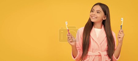 Photo for Dreamy happy teen girl in home terry bathrobe hold toothbrush, health. Banner of child girl with teeth brush, studio portrait, header with copy space - Royalty Free Image