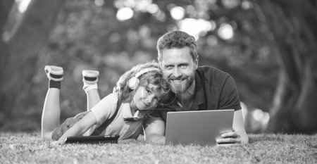 Photo for Online education on laptop. father and son use modern communication technology in park. happy family day. childhood and parenthood. happy boy listen music in headphones. webinar video lesson. - Royalty Free Image