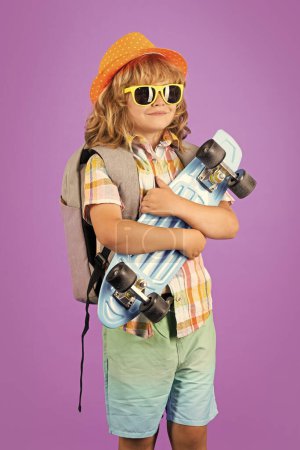 Photo for Kid with skateboard on violet studio background. Child hold skate board. Healthy sport and activity for school kids in summer. Sports fun - Royalty Free Image