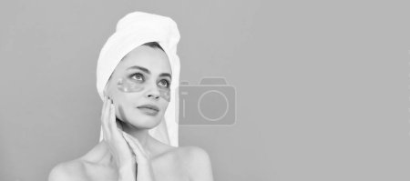 Eye patches, patch under eyes. beautiful girl with terry towel use facial golden eye patch for skin, beauty. Beautiful woman isolated face portrait, banner with mock up copy space
