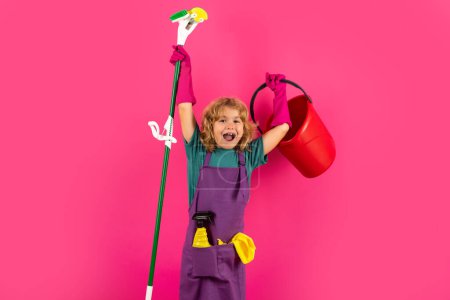 Children helping with housekeeping, cleaning the house. Housekeeping at home. Cute child boy helping with housekeeping on red studio backdround