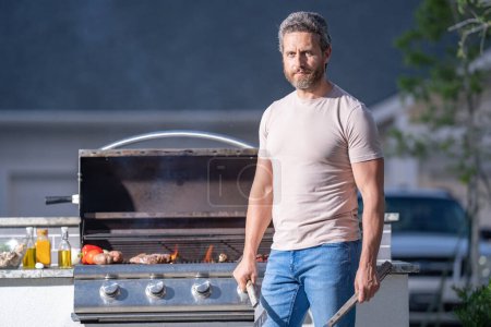 Men cooking on barbecue grill in yard. Cook at a barbecue grill preparing meat