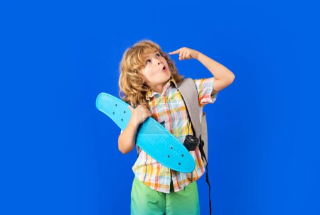Photo for Happy child boy holding skateboard over blue background isolated. Studio portrait of fashion kids - Royalty Free Image