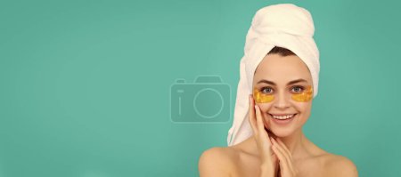 Eye patches, patch under eyes. happy young lady has collagen golden eye patches on face with towel. Beautiful woman isolated face portrait, banner with mock up copy space