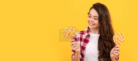 hipster kid with long curly hair hold lollypop. sugar candy on stick. caramel candy shop. sweet childhood life. teen dental care. sweet tooth. yummy. happy girl hold lollipop. lollipop child.