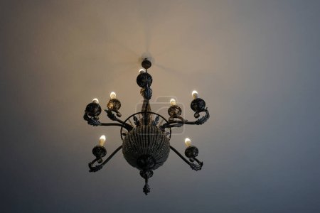 Vieux lustre artistique avec des bougies électriques au plafond