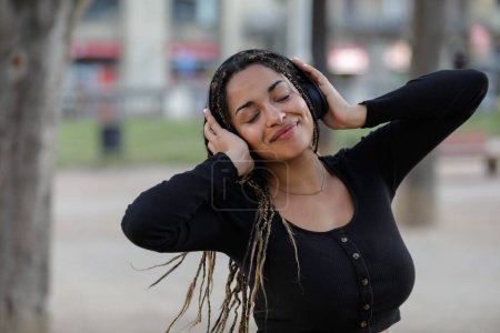 Foto de Mujer relajada con auriculares disfrutando y escuchando música al aire libre - Imagen libre de derechos
