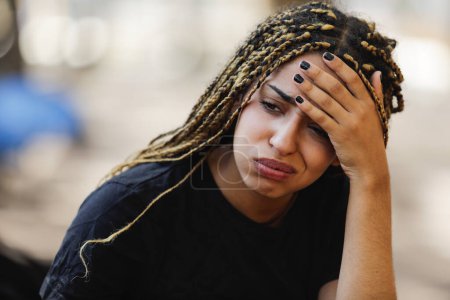 Foto de Mujer joven deprimida o ansiosa sentada en un banco afuera - Imagen libre de derechos