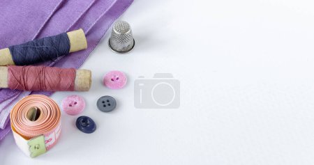 Téléchargez les photos : Accessoires de couture : bobines de fils, boutons, dé à coudre et centimètre sur fond blanc. Espace pour le texte. - en image libre de droit