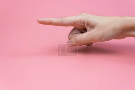 Photo for A woman's hand with an index finger on a pink background. Copy space. - Royalty Free Image