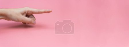Photo for A woman's hand with an index finger on a pink background. Copy space. Banner. - Royalty Free Image