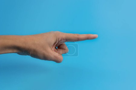 Photo for A woman's hand with an index finger on a blue background. Copy space. - Royalty Free Image