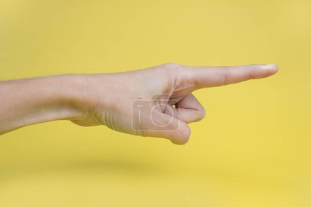 Photo for A woman's hand with an index finger on a yellow background. - Royalty Free Image