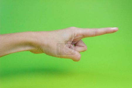 Photo for A woman's hand with an index finger on a green background. - Royalty Free Image