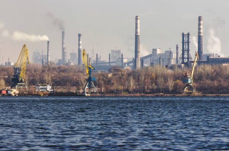 Foto de Vista de la ciudad industrial de Zaporozhye en Ucrania. Emisiones de humos de chimeneas de plantas metalúrgicas. El problema de la contaminación ambiental y el calentamiento global. Puerto de carga. - Imagen libre de derechos