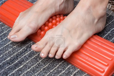 Téléchargez les photos : Massage des pieds féminins avec un masseur d'acupuncture. Acupression. Concept de médecine alternative. - en image libre de droit