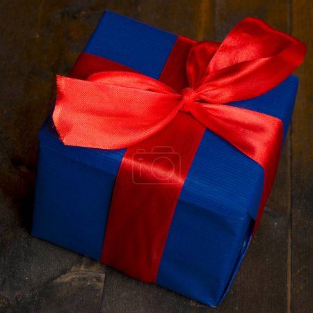 Téléchargez les photos : Boîte cadeau bleue avec arc rouge sur table en bois - en image libre de droit
