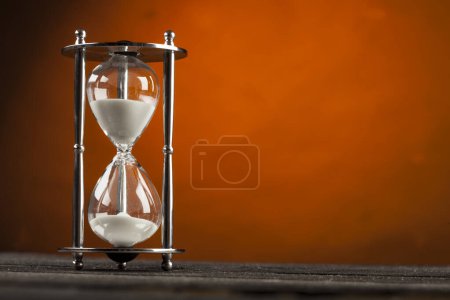 Foto de Reloj de arena de vidrio sobre fondo naranja - Imagen libre de derechos
