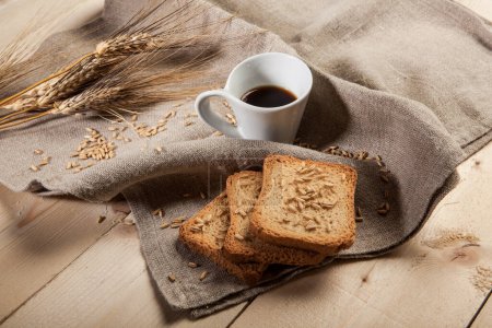 Foto de Rusks, taza de café, trigo y mazorcas de maíz en una mesa - Imagen libre de derechos