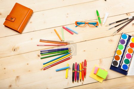 Téléchargez les photos : Aquarelles, crayons, stylos, post-it sur une table en bois - en image libre de droit