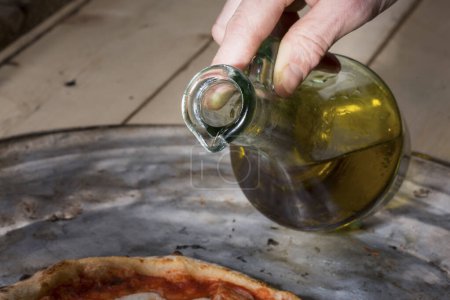 Foto de Un hombre vierte aceite de un cruet en un plato - Imagen libre de derechos