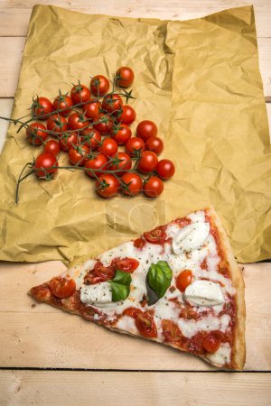 Photo for Pizza wedge with tomatoes and mozzarella on a table viewed from above - Royalty Free Image