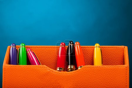 Photo for Orange leather pen holders on a blue background. Colored pens - Royalty Free Image