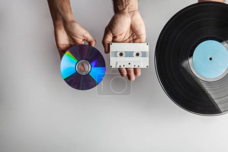 Téléchargez les photos : Mains montrant un vieux disque vinyle, une cassette et un cd - en image libre de droit