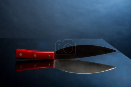 Téléchargez les photos : Couteau avec poignée rouge isolé sur fond noir - en image libre de droit