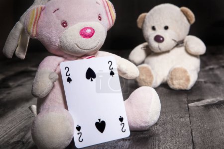 Téléchargez les photos : Petits ours en peluche sur fond en bois tenir les cartes à jouer. Deux de pique - en image libre de droit