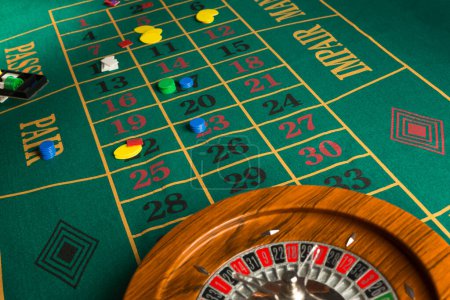 Photo for Roulette in legno isolata sopra un tavolo da gioco verde con fiches colorate - Royalty Free Image