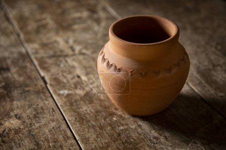 Téléchargez les photos : Belle cruche en céramique isolée sur une vieille table en bois - en image libre de droit