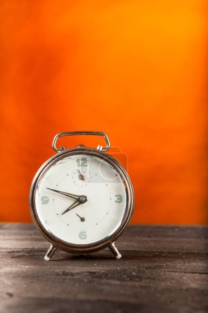 Téléchargez les photos : Horloge ronde vintage sur table en bois et fond orange - en image libre de droit
